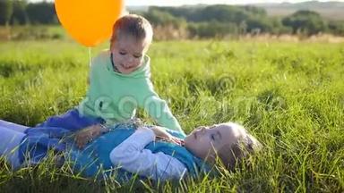 快乐的孩子们在公园里玩耍。 男孩拥抱并亲吻他的妹妹。 气球。 孩子们的笑声和微笑